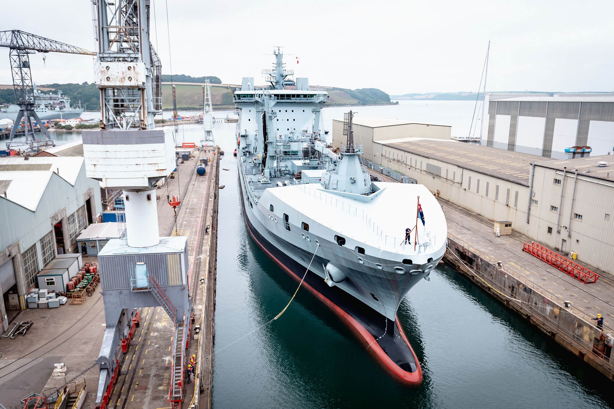 A long grey ship in still harbour waters